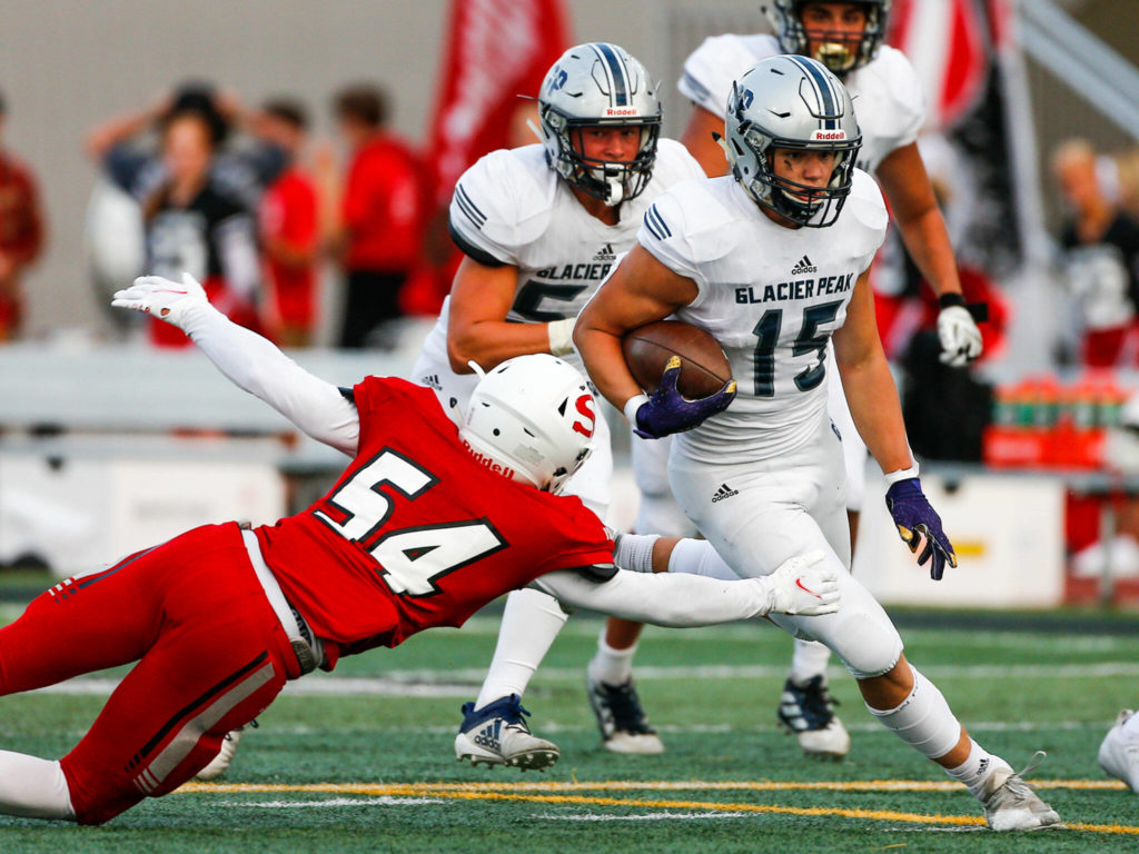 Glacier Peak’s Trey Leckner rushes with Snohomish’s Brayden Ulrich attempting a tackle Friday night at Veteran’s Memorial Stadium in Snohomish September 3, 2021. (Kevin Clark / The Herald)

