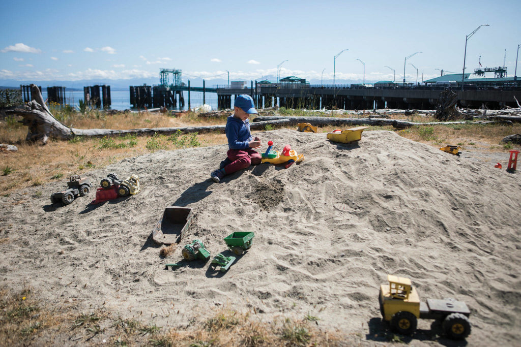 John Roache, 5, plays in the sand with toy trucks at Clinton Beach Park, a good place for kids to blow off steam while waiting for a ferry. (Olivia Vanni / The Herald)
