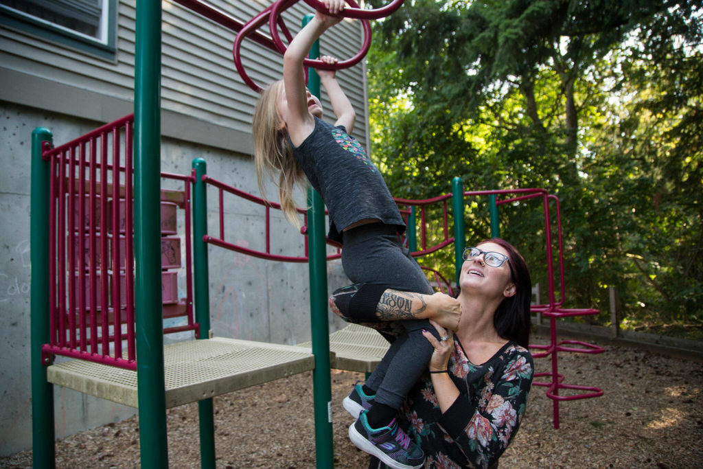 Casey Gibson helps Naomi Rose on the playground bars at Tomorrow’s Hope child care center Tuesday in Everett. (Andy Bronson / The Herald)
