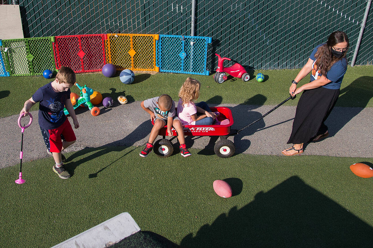 School-age lead Emilee Swenson pulls kids around in a wagon at Tomorrow’s Hope child care center on Tuesday, Sept. 7, 2021 in Everett, Washington. A shortage of child care workers prompted HopeWorks, a nonprofit, to expand its job training programs. Typically, the programs help people with little or no work experience find a job. The new job training program is for people interested in becoming child care workers. (Andy Bronson / The Herald)