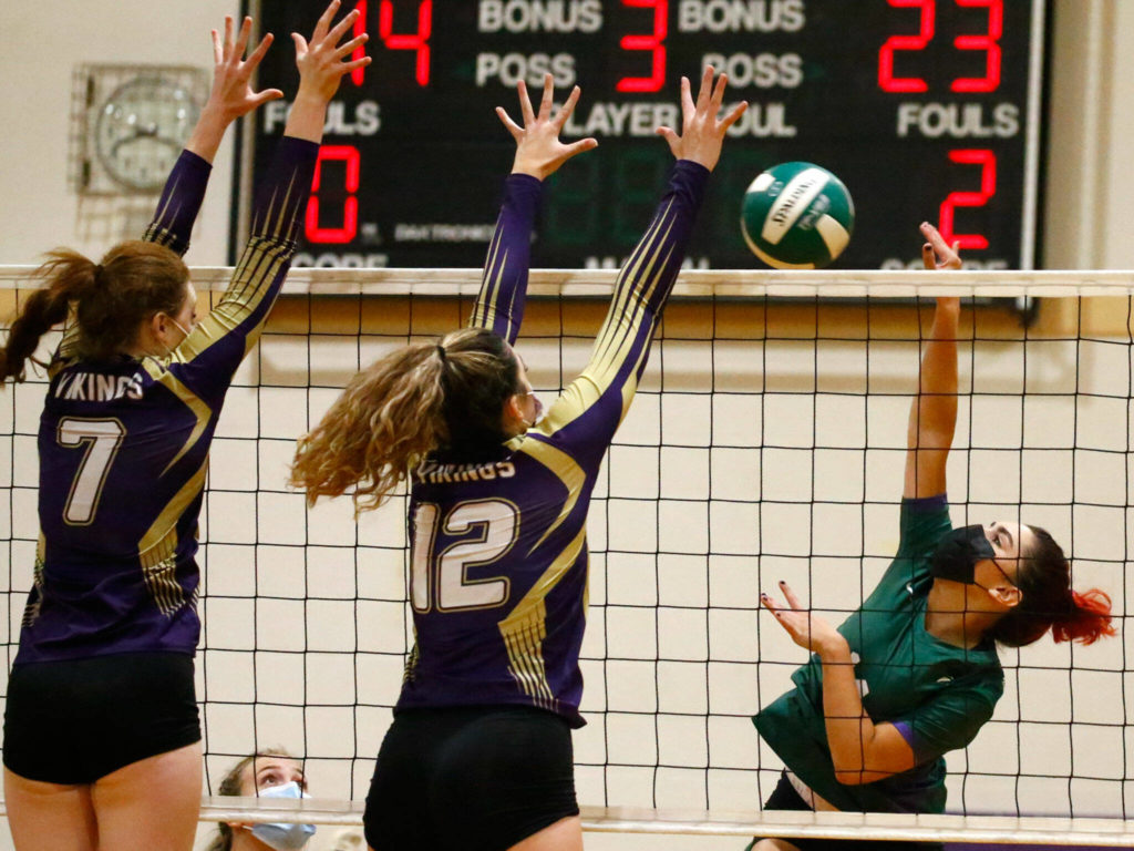 Edmonds-Woodway’s Lucy Barton attempts a spike against Lake Stevens’ Peri Hoshock, left, Kylie Ascher Tuesday night at Edmonds-Woodway High School in Edmonds on September 7, 2021. The Vikings won in straight sets. (Kevin Clark / The Herald)
