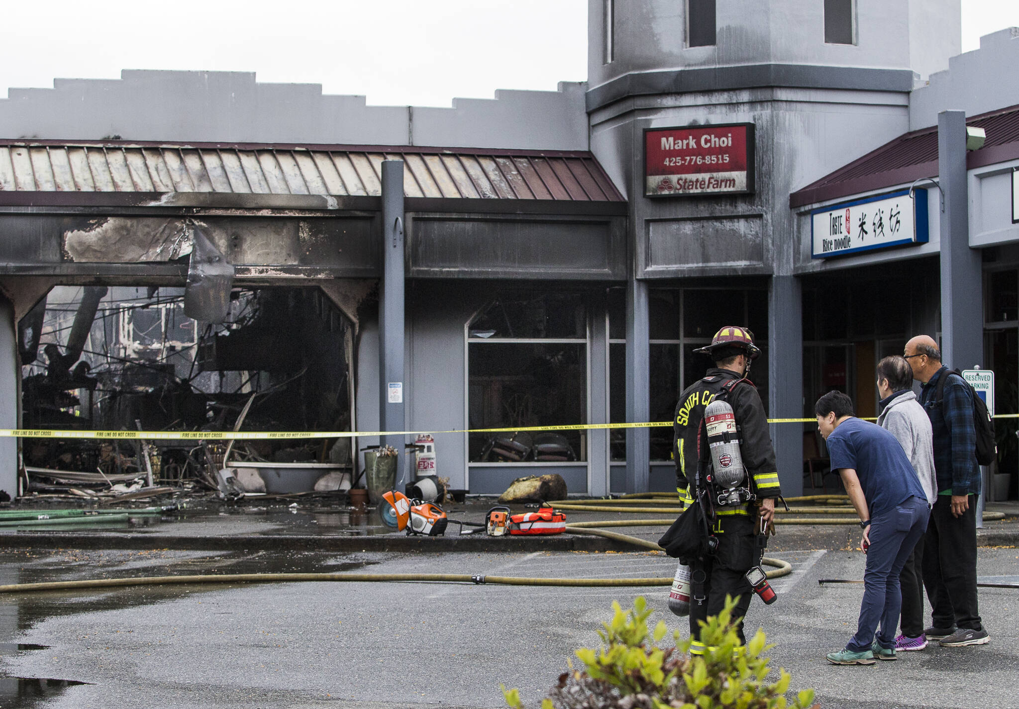 Owners of Taste Rice Noodle talk to a South County firefighter as they survey the damage of a fire at Plum Tree Plaza off of Highway 99 on Saturday, Sept. 11, 2021 in Edmonds, Wa. (Olivia Vanni / The Herald)