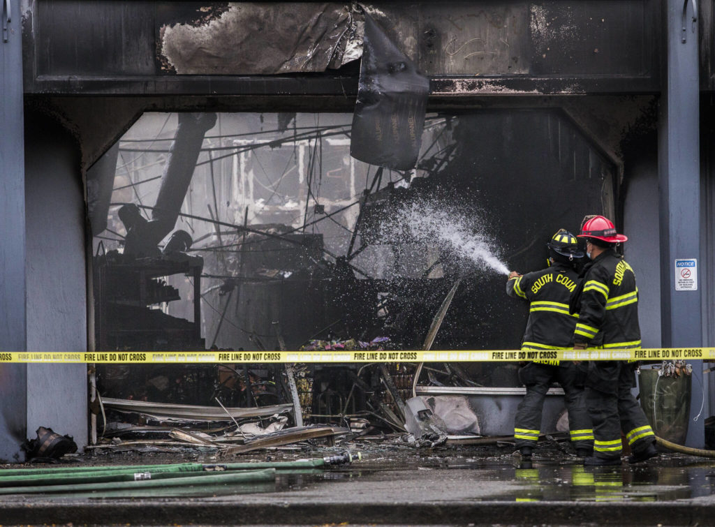 South County firefighters spray water into a business with fire damage at Plum Tree Plaza off of Highway 99 on Saturday, Sept. 11, 2021 in Edmonds, Wa. (Olivia Vanni / The Herald)
