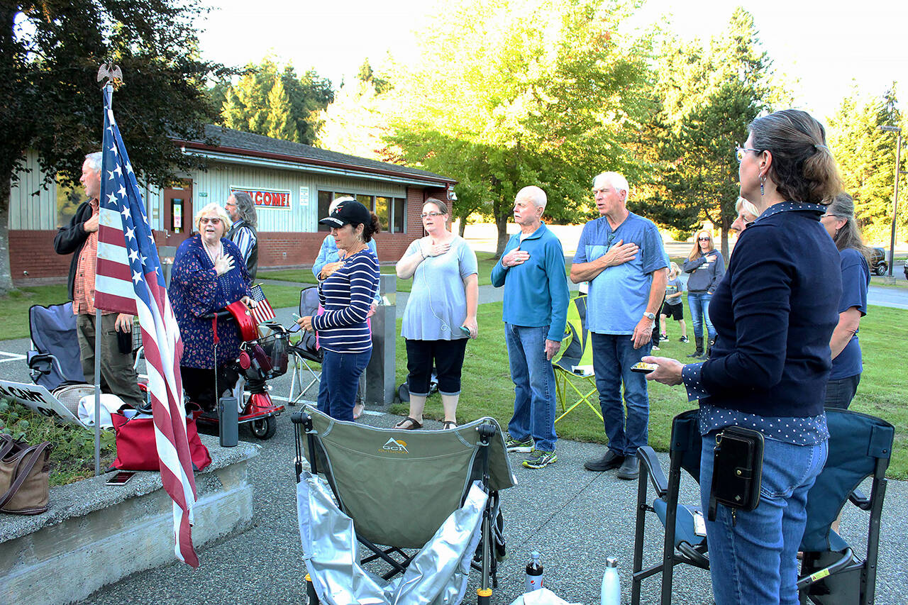 Community members stand and recite the Pledge of Allegiance while listening to a South Whidbey School District board meeting. (Karina Andrew / Whidbey News-Times)