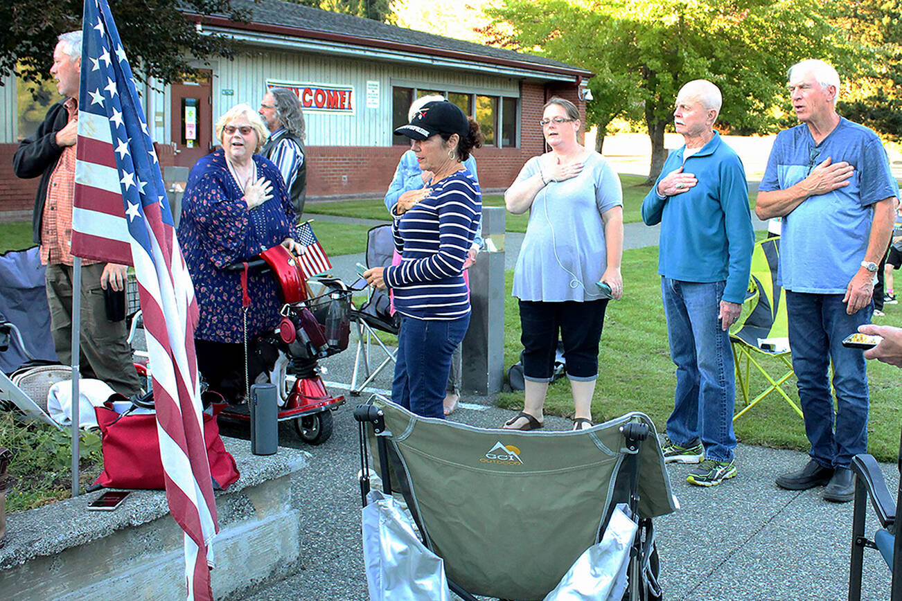 Community members stand and recite the Pledge of Allegiance while listening to a South Whidbey School District board meeting. (Photo by Karina Andrew/Whidbey News-Times)