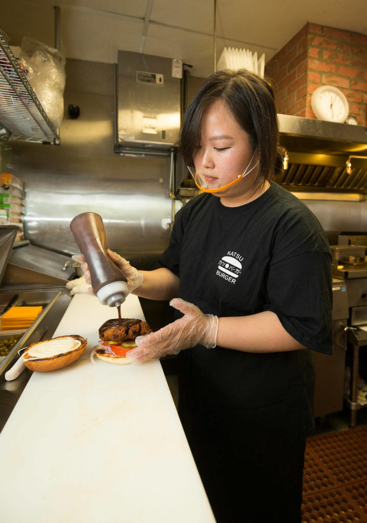 Chef-owner Hannah Ha prepares a Tokyo Classic burger on a housemade brioche bun at Katsu Burger in Lake Stevens. (Andy Bronson / The Herald)
