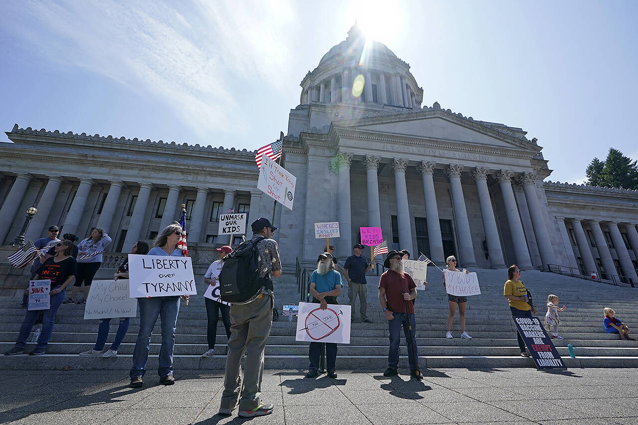 Protesters who oppose mask and COVID-19 vaccine mandates gather outside the Legislative Building on Aug. 18 at the Capitol in Olympia. On Friday, Washington state troopers, prison correctional officers, ferry workers and other public sector employees filed a lawsuit to try to overturn Gov. Jay Inslee’s vaccine mandate. (AP Photo/Ted S. Warren, file)