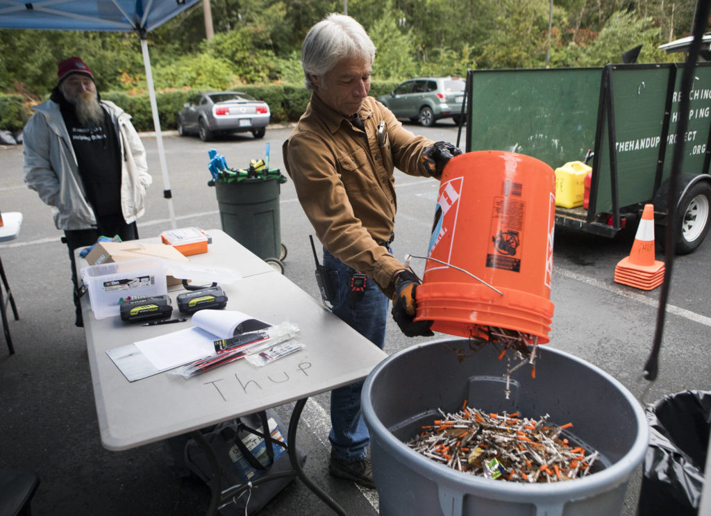 Tony Thompson, operations coordinator with The Hand Up Project, dumps collected needles into a trash bin Sunday near Everett. (Olivia Vanni / The Herald)
