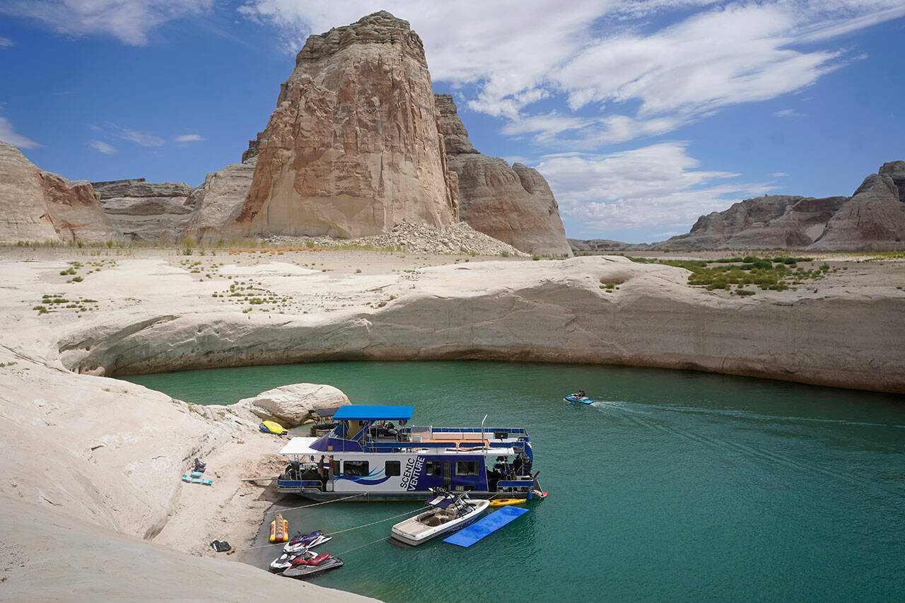 A houseboat rests in a cove at Lake Powell, July 30, near Page, Ariz. This summer, lake and river water levels hit a historic low amid a climate change-fueled megadrought engulfing the U.S. West. (Rick Bowmer / Associated Press)