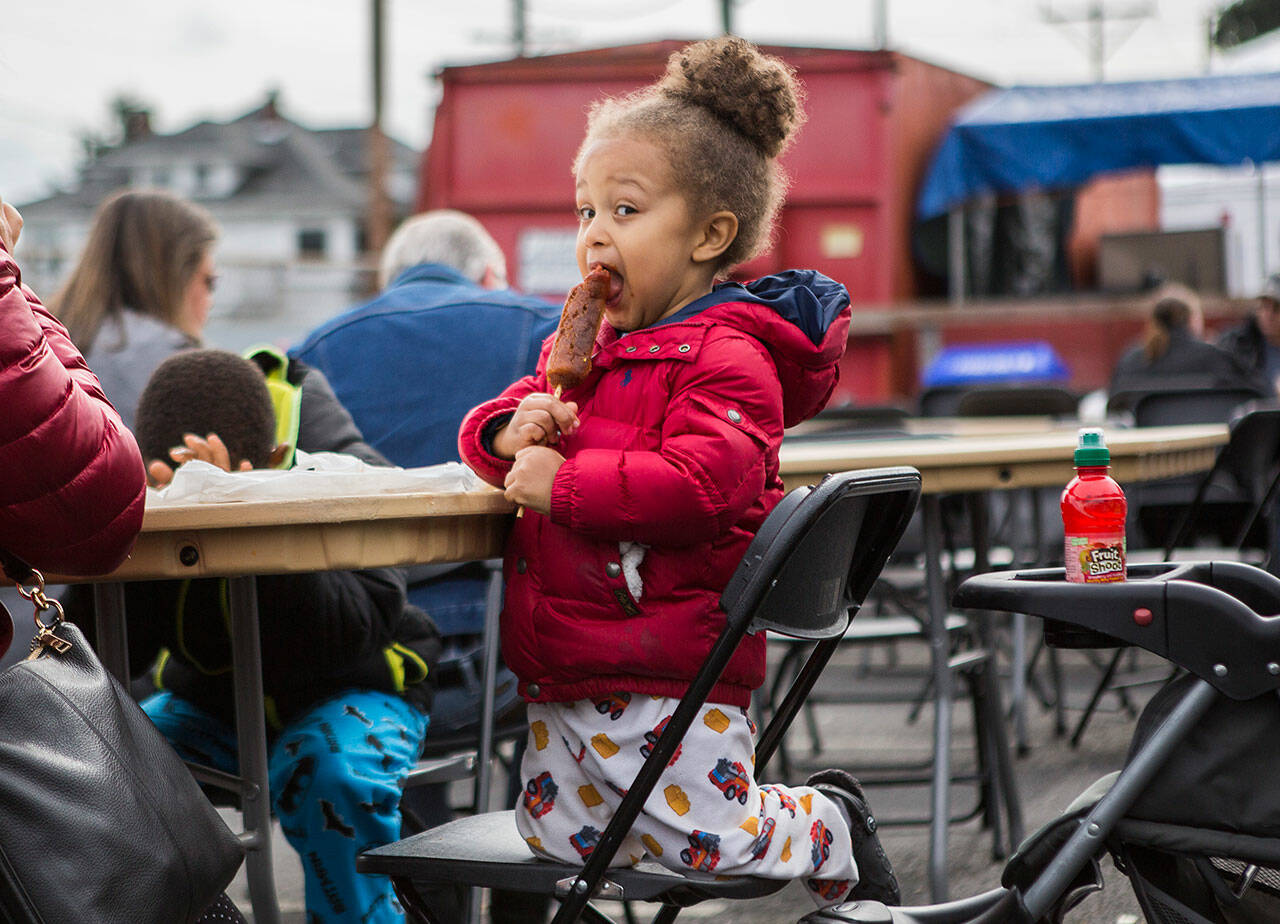 A child enjoys a sausage on a stick at the Everett Sausage Festival in 2019. This year’s festival is slated for Sept. 24-26. (Olivia Vanni / The Herald)
