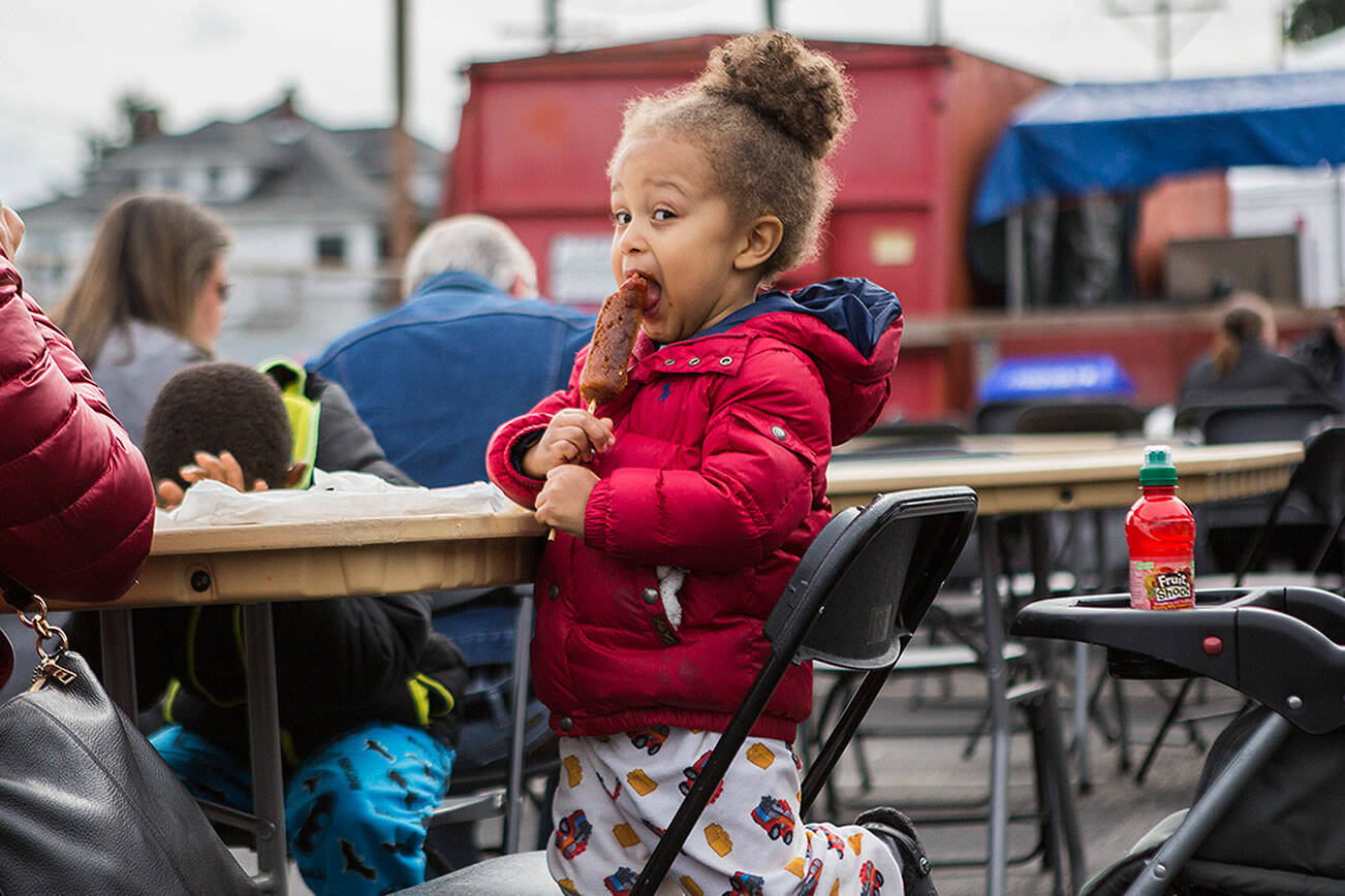 A child enjoys a sausage on a stick during Sausage Fest on Sunday, Sept. 29, 2021 in Everett, Wash. (Olivia Vanni / The Herald)
