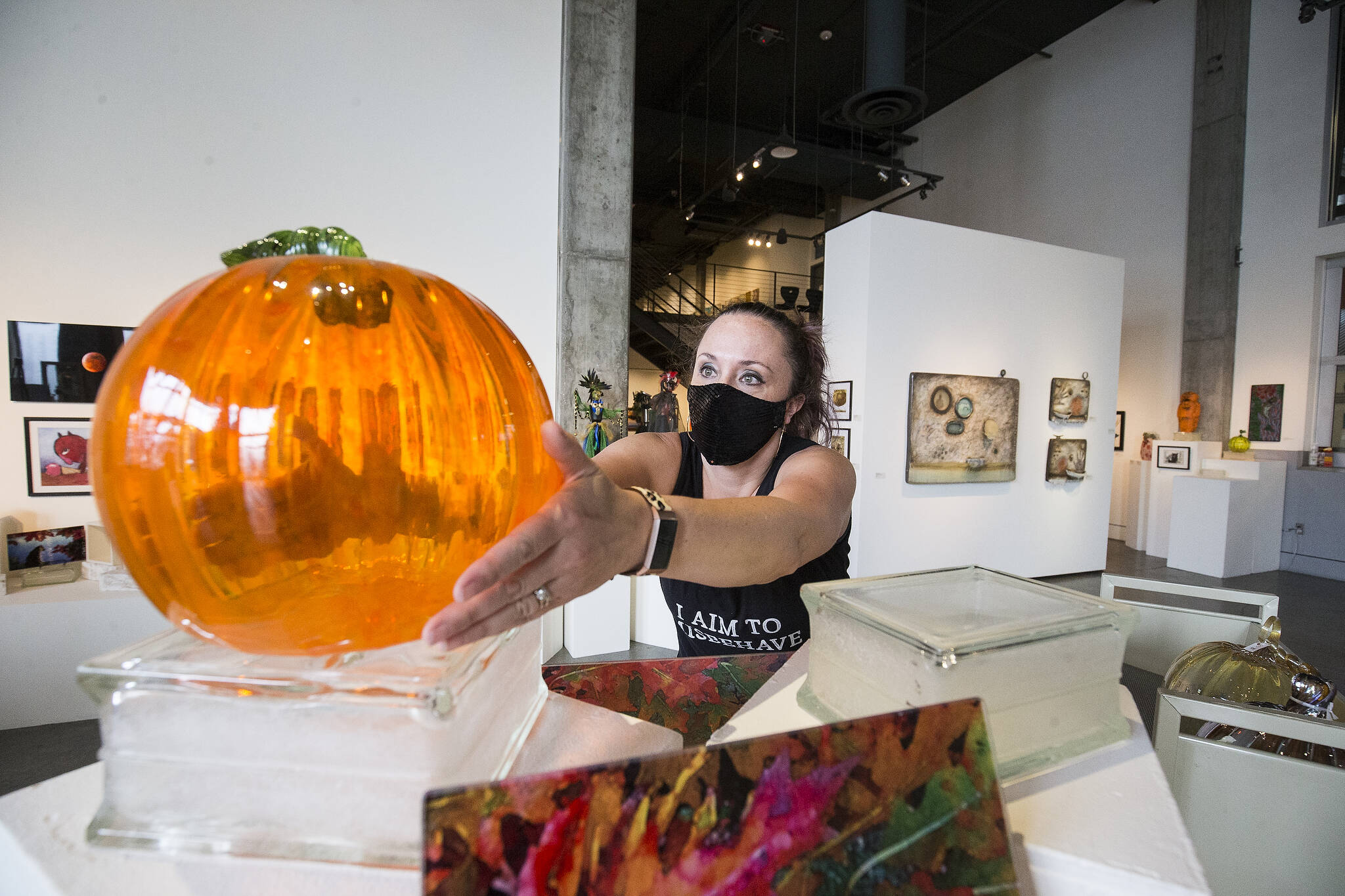 Josey Wise puts one of hundreds of glass pumpkins on a display at the Schack Art Center on Sept. 22 for Schack-toberfest. The Everett glass pumpkin patch and harvest art festival runs from Sept. 23 to Nov. 6. (Andy Bronson / The Herald)