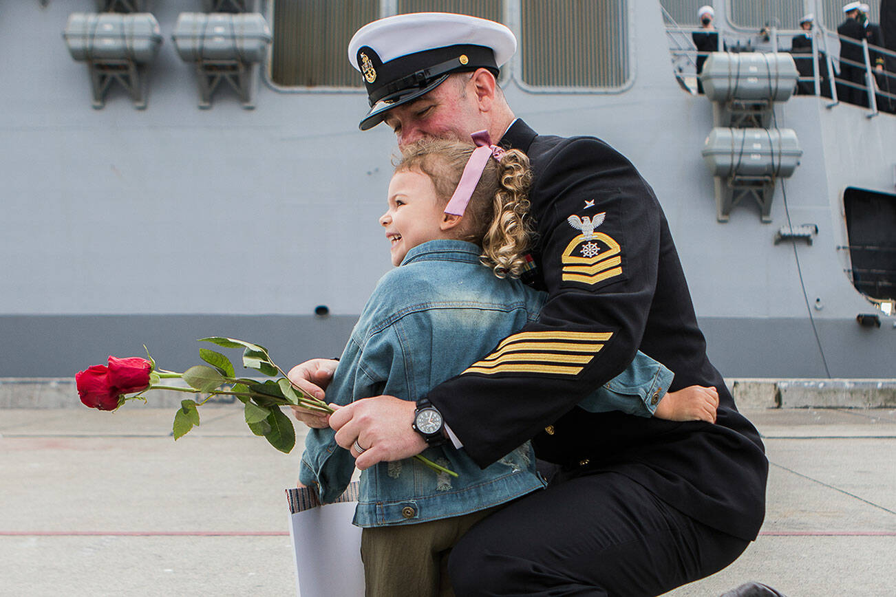 Harlow Gore, 3, looks back at her mother and smiles while she hugs her dad, Senior Chief Jerry Gore, after he returns from deployment aboard the USS Kidd on Friday, Sept. 24, 2021 in Everett, Wa. (Olivia Vanni / The Herald)