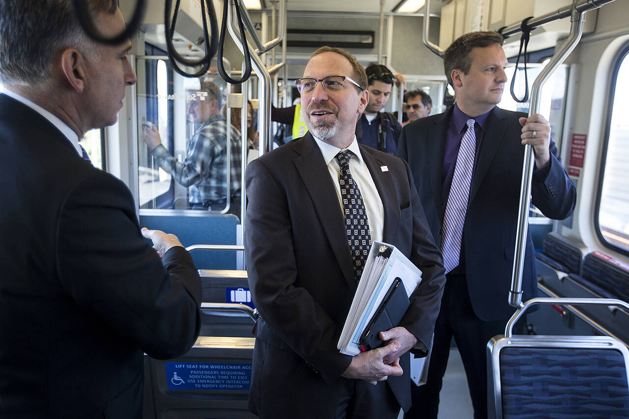 Sound Transit CEO Peter Rogoff (center) takes a ride on light rail in 2016 with King County Executive Dow Constantine (left) on Wednesday, Sept. 21. (Ian Terry / Herald file)
