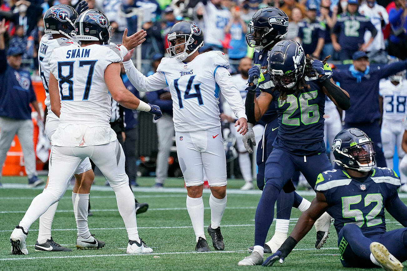 Tennessee Titans kicker Randy Bullock (14) celebrates with tight end Geoff Swaim (87) as Seattle Seahawks defensive back Ryan Neal (26) reacts after Bullock kicked a field goal in overtime to give the Titans a 33-30 win in an NFL football game, Sunday, Sept. 19, 2021, in Seattle. (AP Photo/Elaine Thompson)