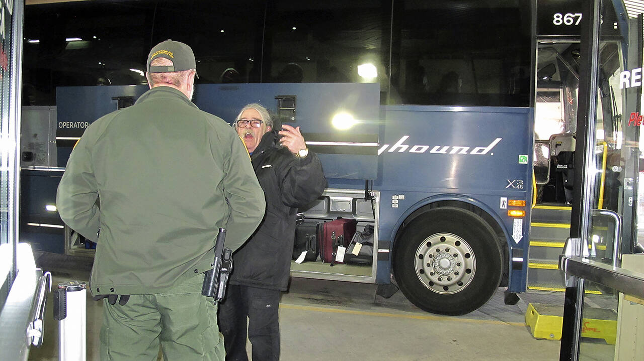 In this Feb. 13, 2020 photo, a worker (right) speaks with a Customs and Border Protection agent seeking to board a Greyhound bus headed for Portland at the Spokane Intermodal Center. (AP Photo/Nicholas K. Geranios, file)