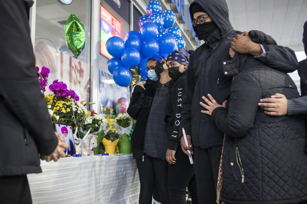 TejPal Singh’s children and family members approach a small memorial table set up at his candlelight vigil Wednesday in Lynnwood. (Olivia Vanni / The Herald)
