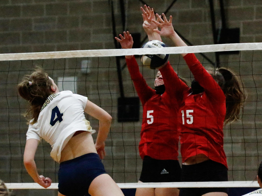 Arlington’s Malia Shepherd gets through the defense on Snohomish’s Mia Toroni (5) and Snohomish’s Anneke Hanson (15) Wednesday night at Arlington High School on September 29, 2021. The Eagles won in straight sets. (Kevin Clark / The Herald)

