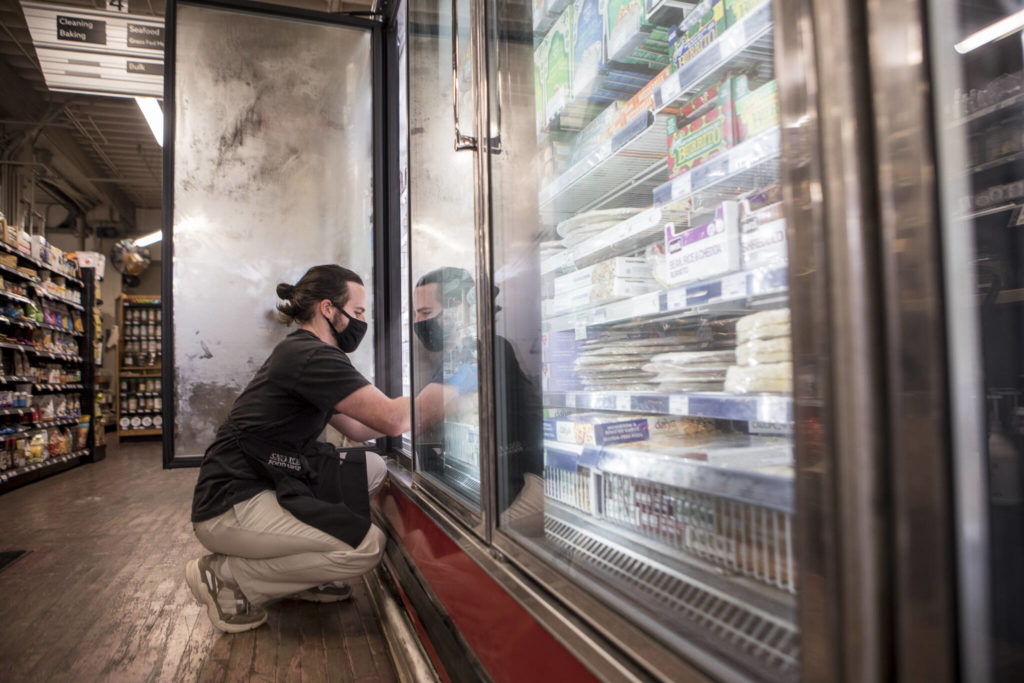 Ian Daw, a 14-year employee and retail manger, stocks the frozen food section at the Sno-Isle Food Co-op in Everett. (Olivia Vanni / The Herald) 
