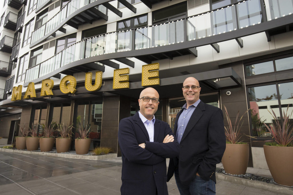 Craig (left) and Andy Skotdal in front of their newest development, the Marquee Apartments on Wetmore Street in Everett. (Andy Bronson / The Herald)
