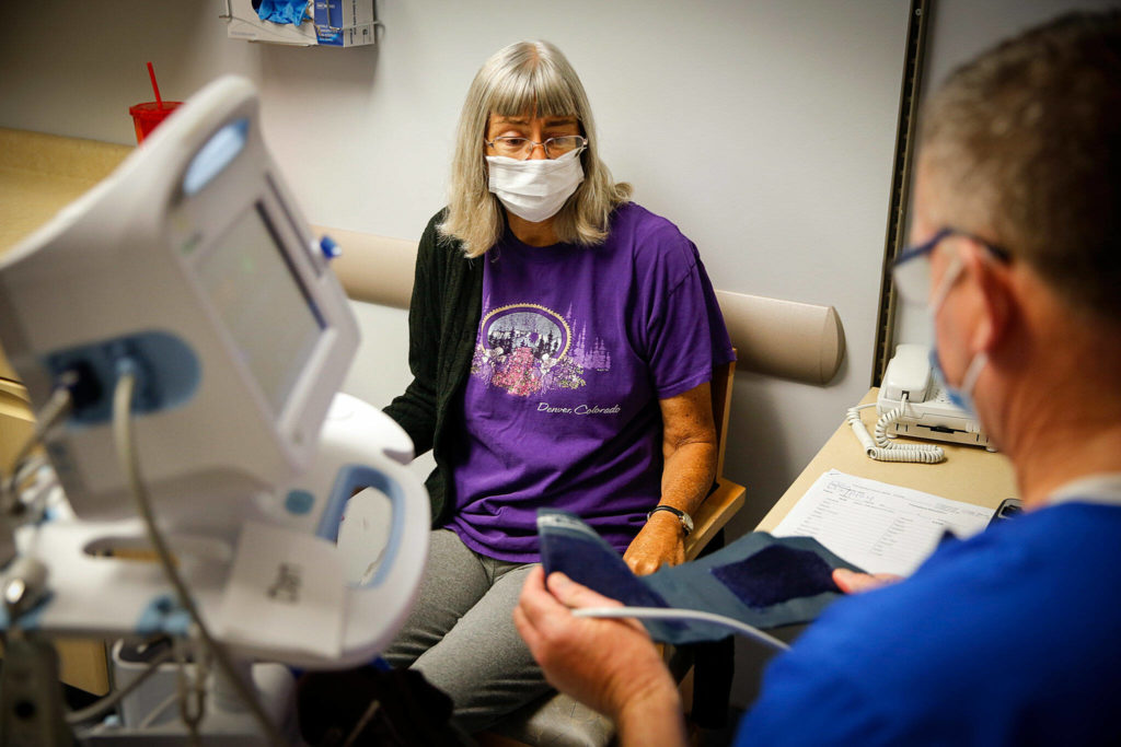 Deena Jones (left) gets her vitals measured by Daniel Johnson during one of her twice weekly checkups at UW Medicine in Seattle on Sept. 30. (Kevin Clark / The Herald)
