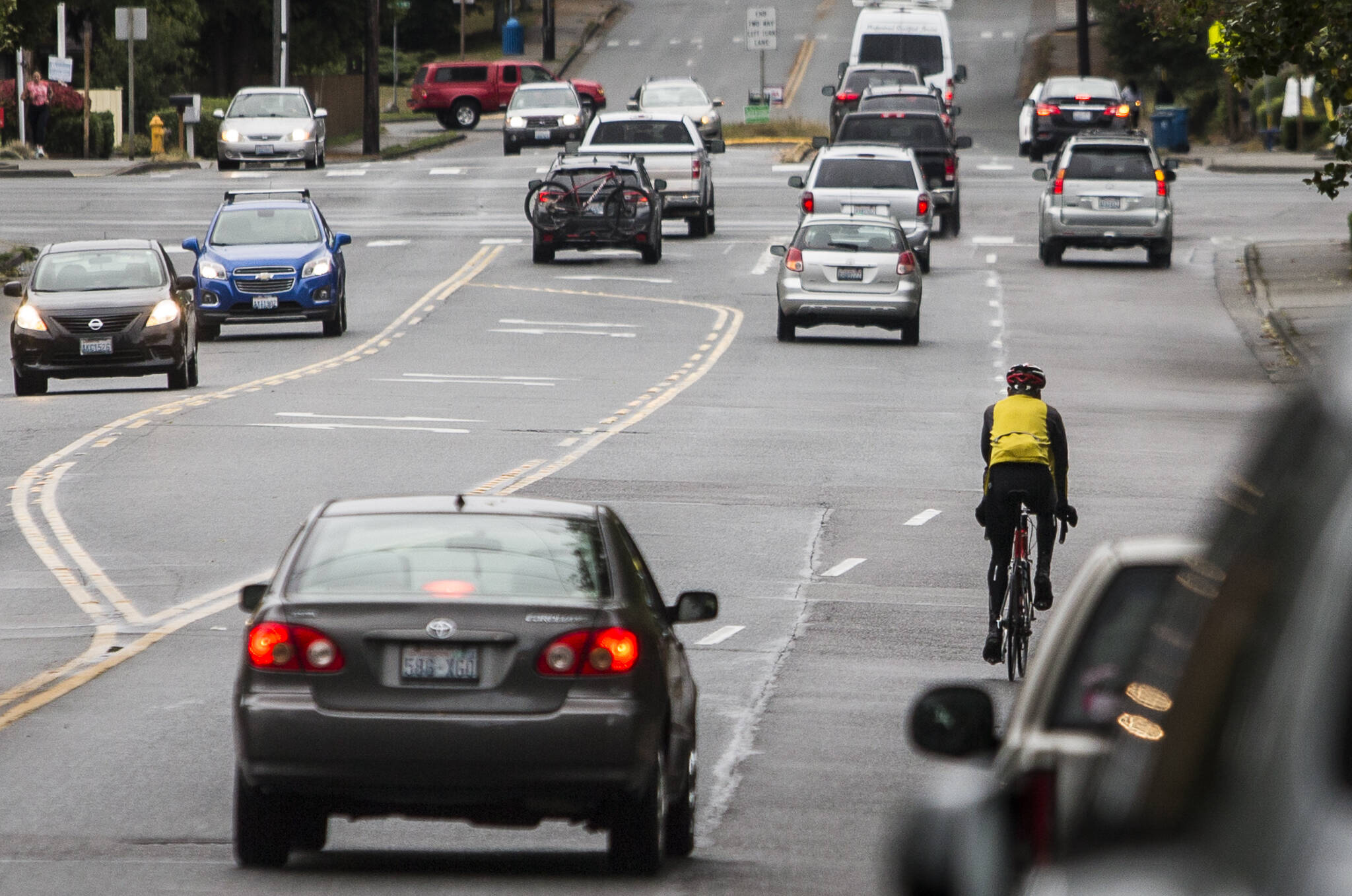 A bicyclist navigates car traffic while riding south along 100th Avenue W toward the intersection with Highway 104 on Tuesday in Edmonds. The city is considering two options for dedicated bike space, which would reduce at least one vehicle lane. (Olivia Vanni / The Herald)