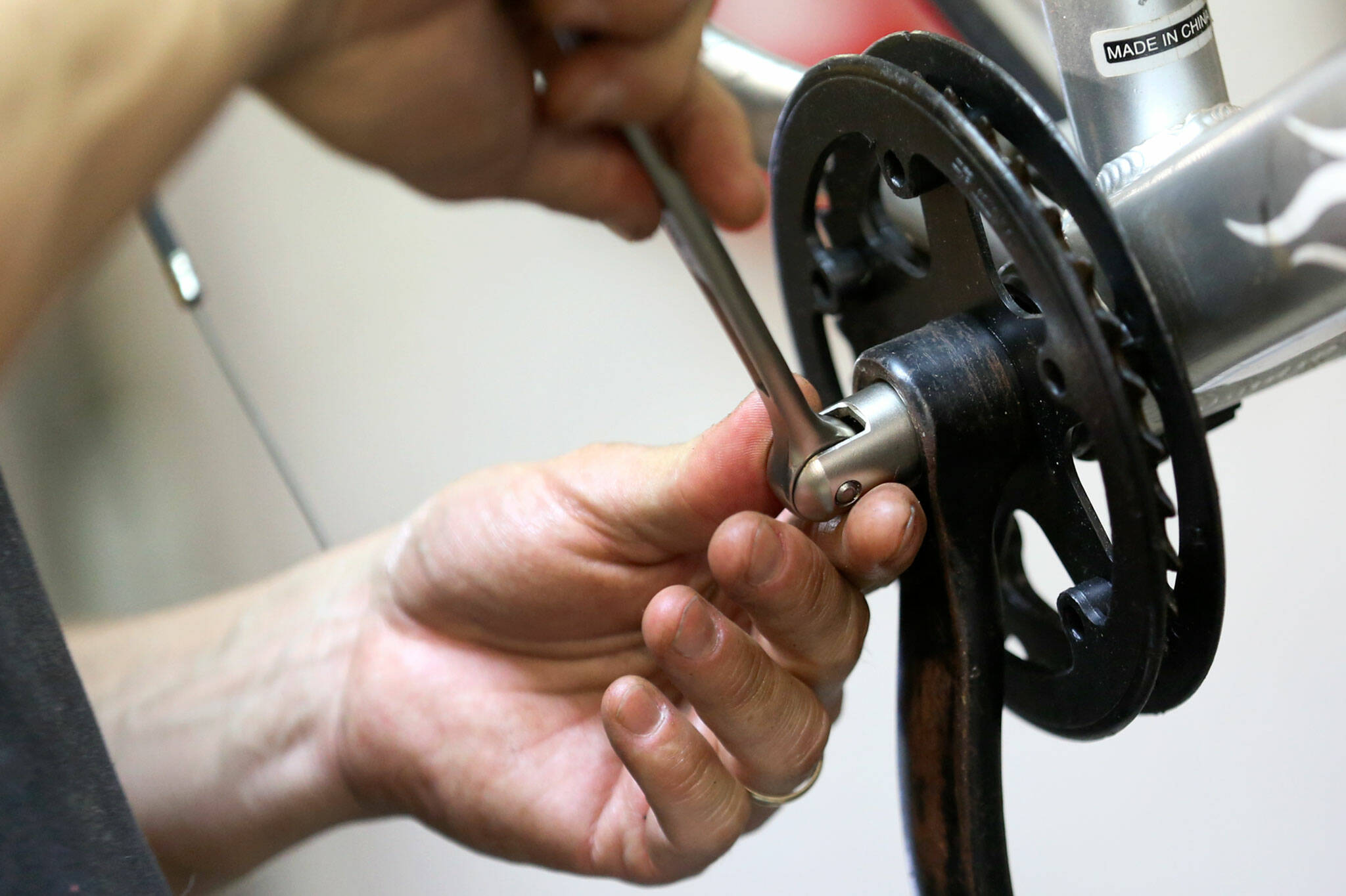 A volunteer works on a bicycle May 30, 2019, at Sharing Wheels Community Bike Shop in Everett. The nonprofit bike shop is asking for children’s bike donations and volunteers to help repair them as gifts through Christmas House. (Kevin Clark / Herald file)