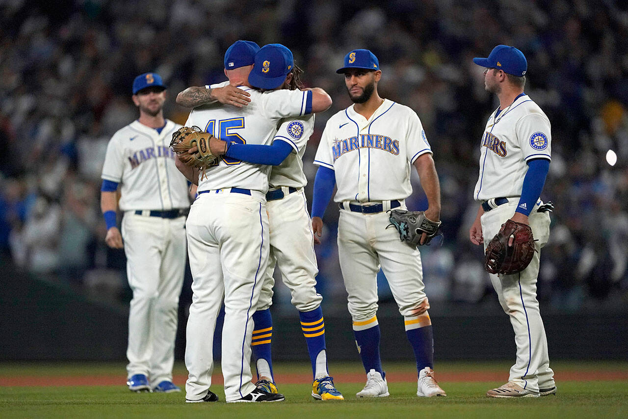 Seattle Mariners third baseman Kyle Seager (15) hugs teammates as he is subbed out in the ninth inning of Sunday’s game against Los Angeles Angels in Seattle. (AP Photo/Ted S. Warren)