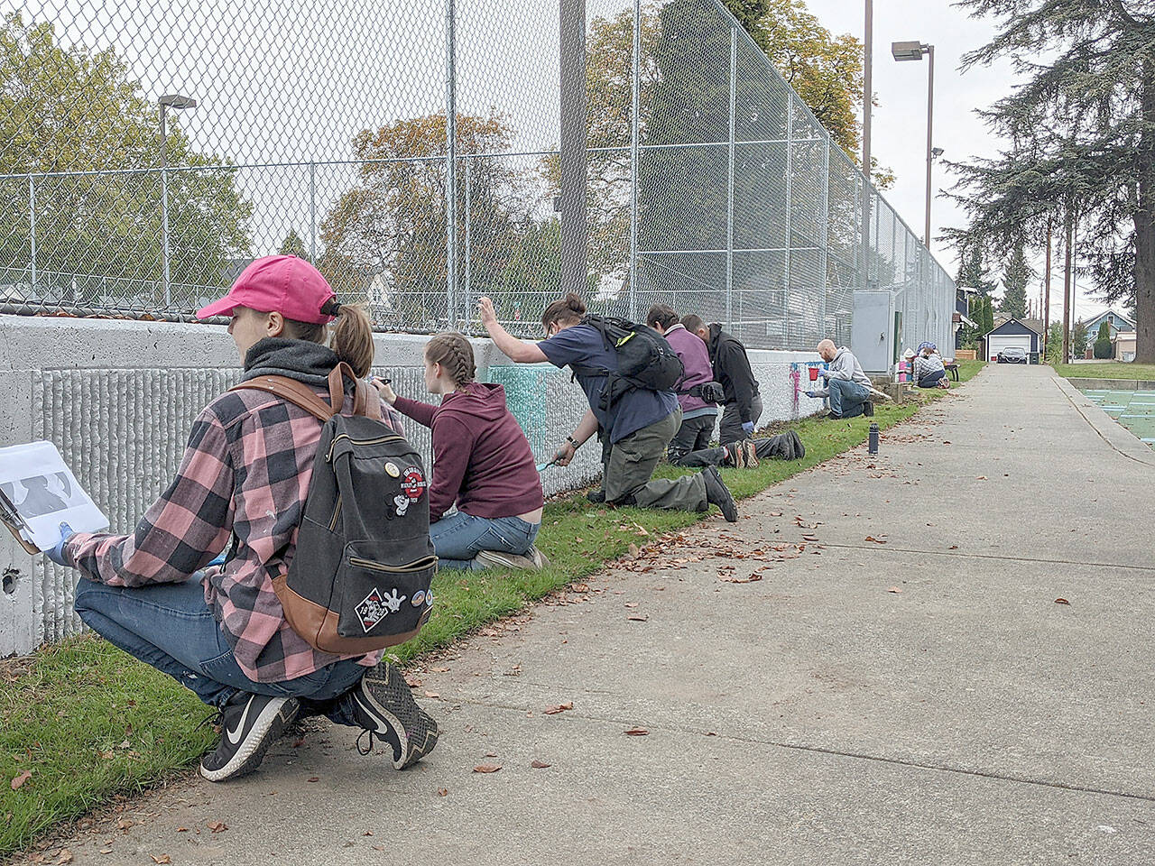 People work on the painted mural of the tennis courts wall at Clark Park in Everett. The Bayside Neighborhood Association organized the event, and Erika Flak designed the mural. (Jay Austria)