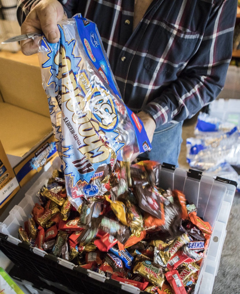 Stephen Fay pours candy into a large storage container at his home Friday in Marysville. (Olivia Vanni / The Herald)
