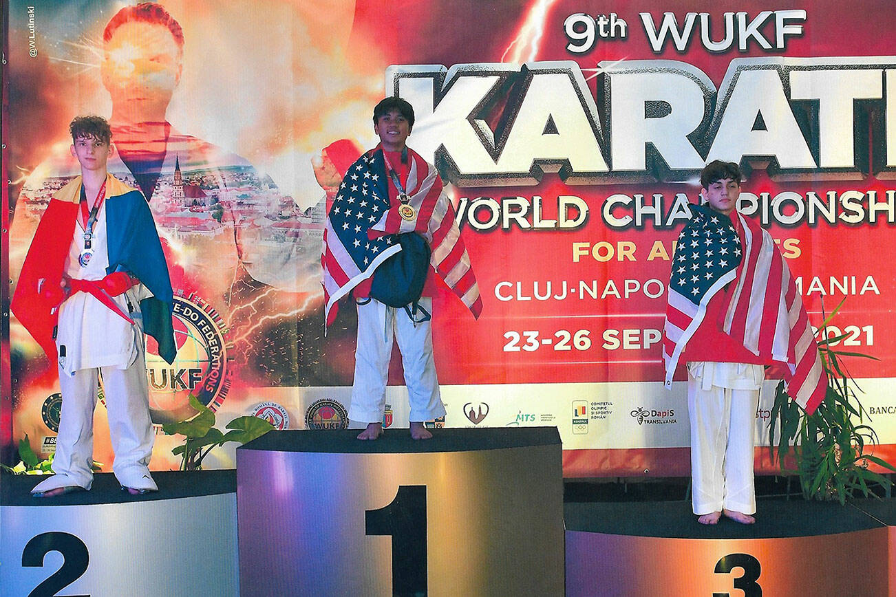 Lawrence Muhat (center), of Lake Stevens, stands on the podium after winning the Kumite gold medal at the WUKF World Karate Championships held Sept. 23-26 in Cluj-Napoca, Romania. (Photo courtesy of the Muhat family)