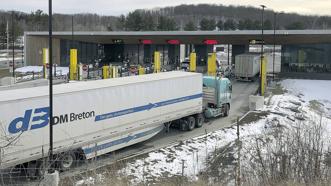 In this March 2020 photo, truck traffic from Canada waits to cross the border into the United States in Derby Line, Vermont. The U.S. will reopen its land borders to nonessential travel next month. (AP Photo/Wilson Ring, File)
