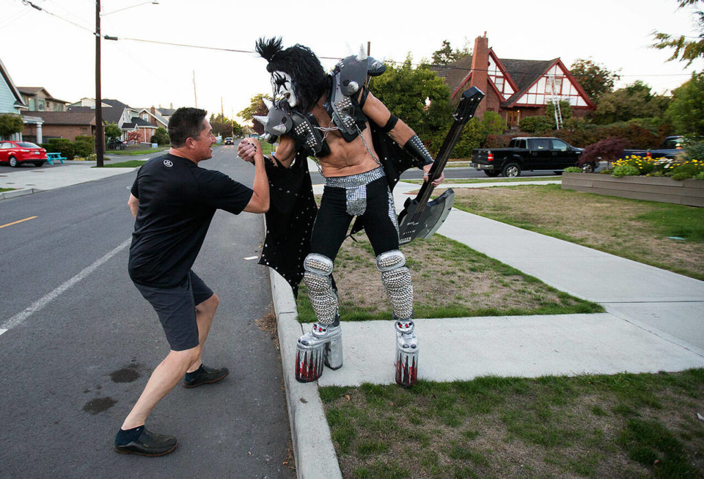 Dressed as Gene Simmons of Kiss fame, Everett firefighter and paramedic Jack Murrin and neighbor John Tanaka greet each other out on the street as Murrin heads out to a open mic session at Cafe Zippy in 2017 in Everett. (Andy Bronson / The Herald)
