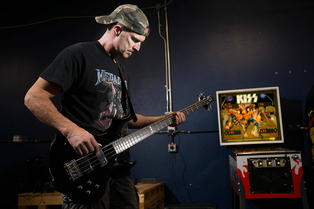 Gene Simmons impersonator, Jack Murrin practices on there bass guitar at his storage building on Thursday, Oct. 21, 2021 in Everett, Washington. Murrin, 51, a firefighter and impersonator, is putting on a 2-hour KISS concert with 19 songs in front of his north Everett home on Halloween.  (Andy Bronson / The Herald)