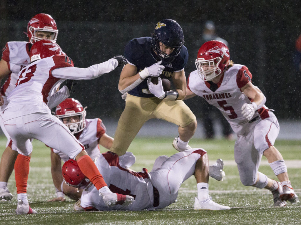 Arlington’s Gage Price leaps over a Marysville-Pilchuck player Friday during the game in Arlington. (Olivia Vanni / The Herald)
