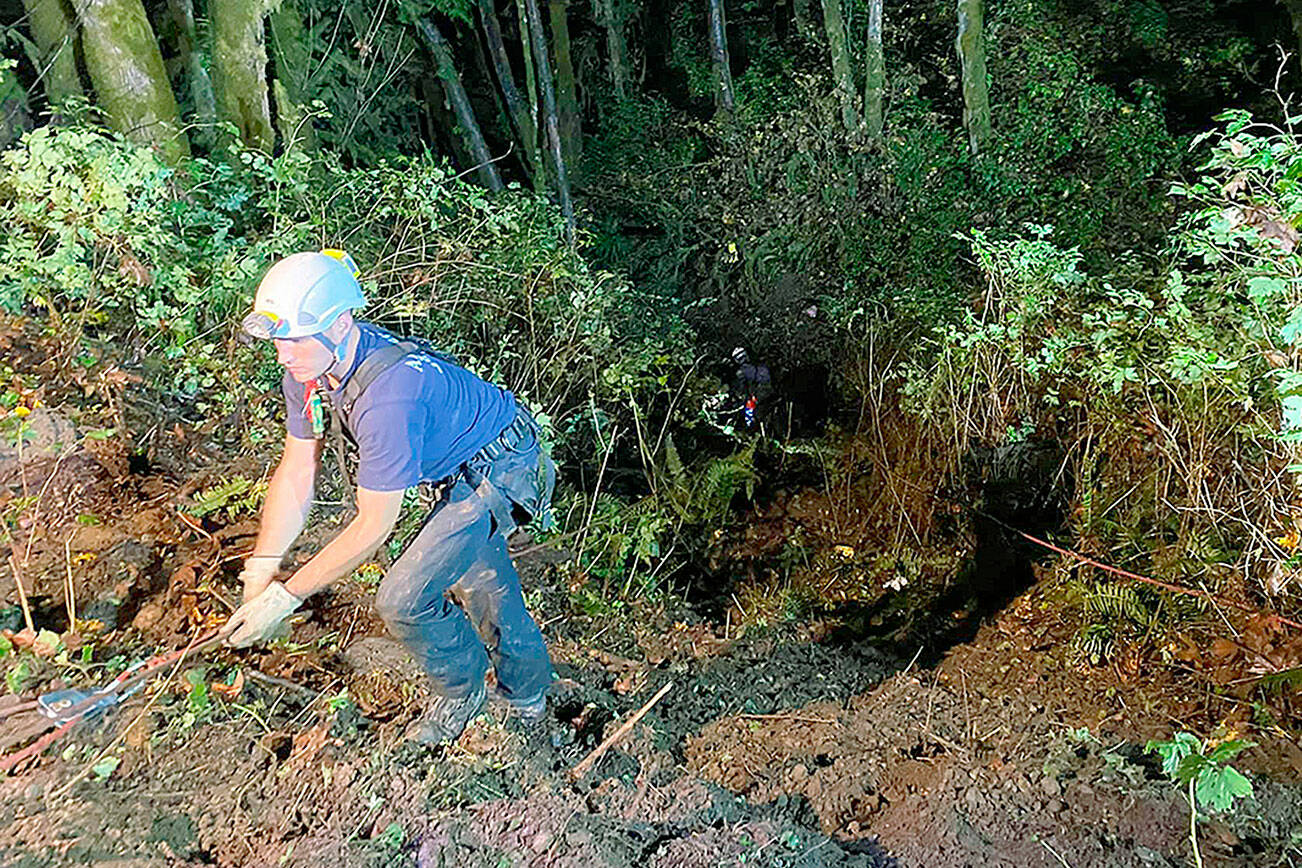 An emergency responder uses a line to navigate the steep slope along a Forest Service road where seven people were injured Saturday when a vehicle went off the road near the Boulder River trailhead west of Darrington. (Darrington Fire District)