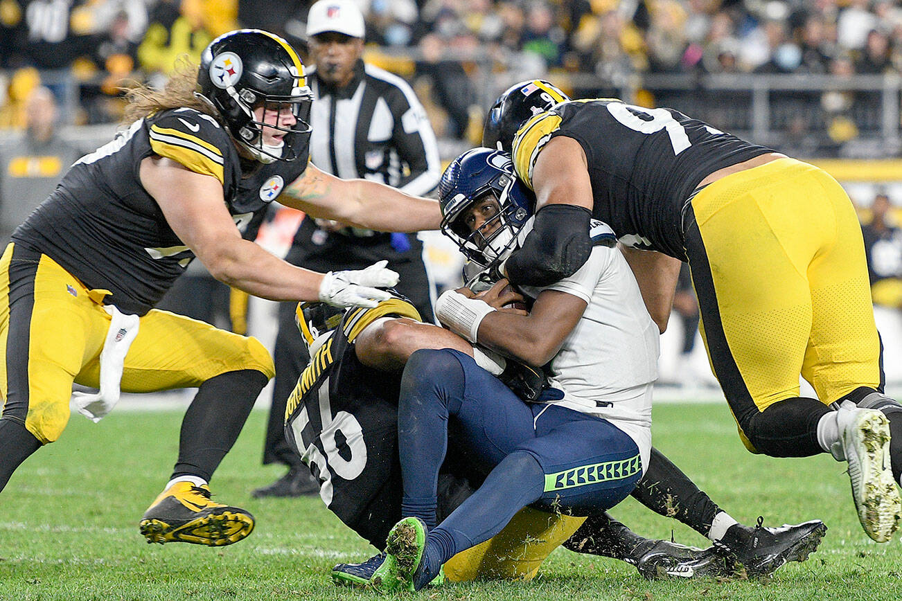 Seattle Seahawks quarterback Geno Smith (7) is sacked by Pittsburgh Steelers outside linebacker Alex Highsmith (56), defensive end Henry Mondeaux (99), left, and defensive end Chris Wormley (95), right, during the second half an NFL football game, Sunday, Oct. 17, 2021, in Pittsburgh. (AP Photo/Don Wright)