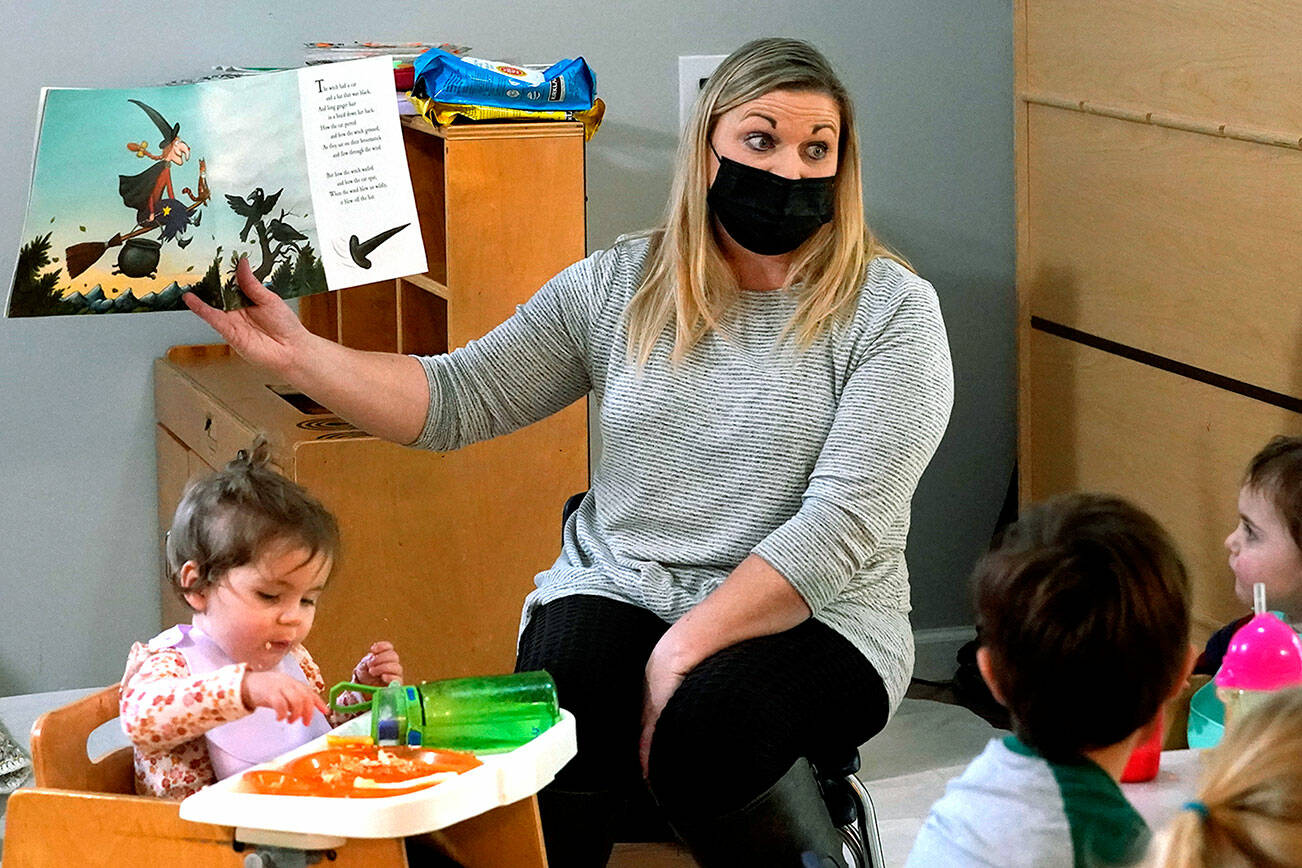 Amy McCoy reads a book to preschoolers as they finish their lunch at her Forever Young Daycare facility, Monday, Oct. 25, 2021, in Mountlake Terrace, Wash. Child care centers once operated under the promise that it would always be there when parents have to work. Now, each teacher resignation, coronavirus exposure, and day care center closure reveals an industry on the brink, with wide-reaching implications for an entire economy's workforce. (AP Photo/Elaine Thompson)