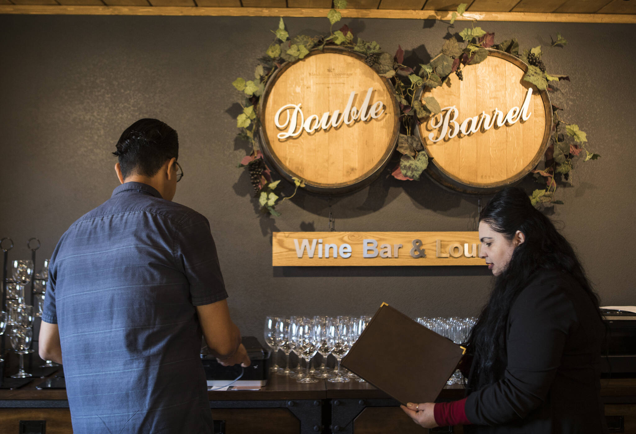 Double Barrel Wine Bar and Lounge owner Lionel Madriz and his wife, Ana Madriz, talk through menu items. (Olivia Vanni / The Herald)