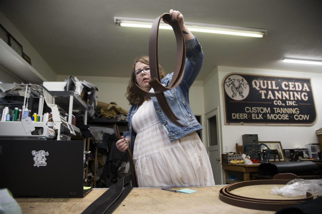 Owner Lacey Coragiulo sorts raw belt leathers at Quil Ceda Leather in Marysville. (Andy Bronson / The Herald) 
