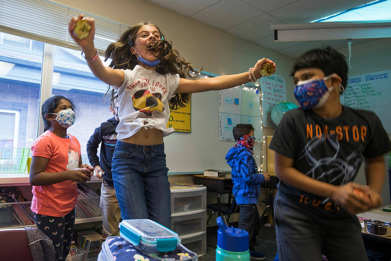 Second grader Emma Bahboud jumps for joy after splitting  an apple in half using just heir hands during class at Penny Creek Elementary School on Thursday, Oct. 28, 2021 in Everett, Washington.  (Andy Bronson / The Herald)