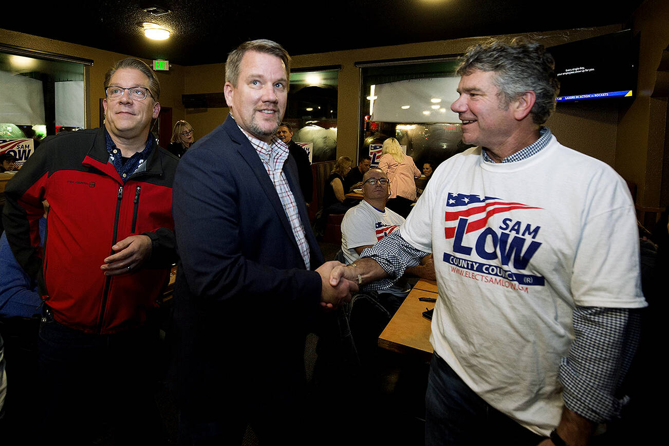 Snohomish County Councilman Sam Low (center) is congratulated by Snohomish Regional Fire and Rescue Fire Chief Kevin O'Brien (right) as results show Low in the lead during an election night party at Nachos Family Mexican Restaurant on Tuesday, Nov. 2, 2021 in Lake Stevens, Washington.  (Andy Bronson / The Herald)