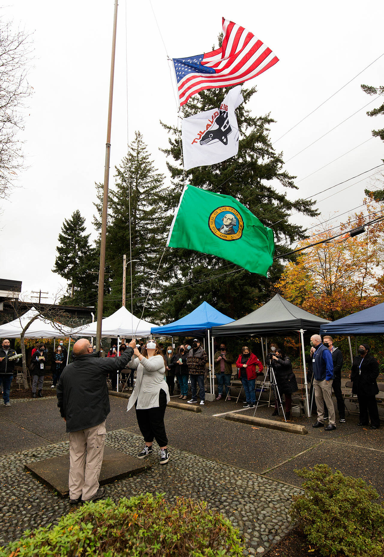 Tony Hatch (right) raises the Tulalip Tribes flag during a ceremony at the Marysville School District Educational Service Center on Thursday. (Andy Bronson / The Herald)