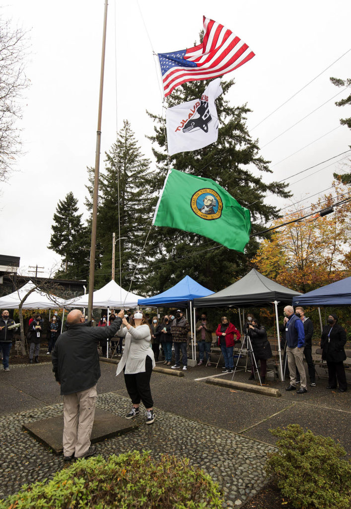 Tony Hatch (right) raises the Tulalip Tribes flag during a ceremony at the Marysville School District Educational Service Center on Thursday. (Andy Bronson / The Herald)
