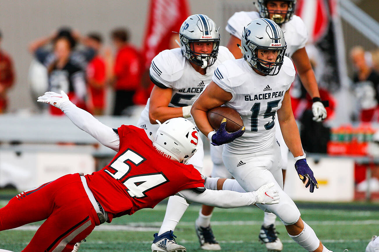 Glacier Peak's Trey Leckner rushes with Snohomish's Brayden Ulrich attempting a tackle Friday night at Veteran's Memorial Stadium in Snohomish September 3, 2021. (Kevin Clark / The Herald)