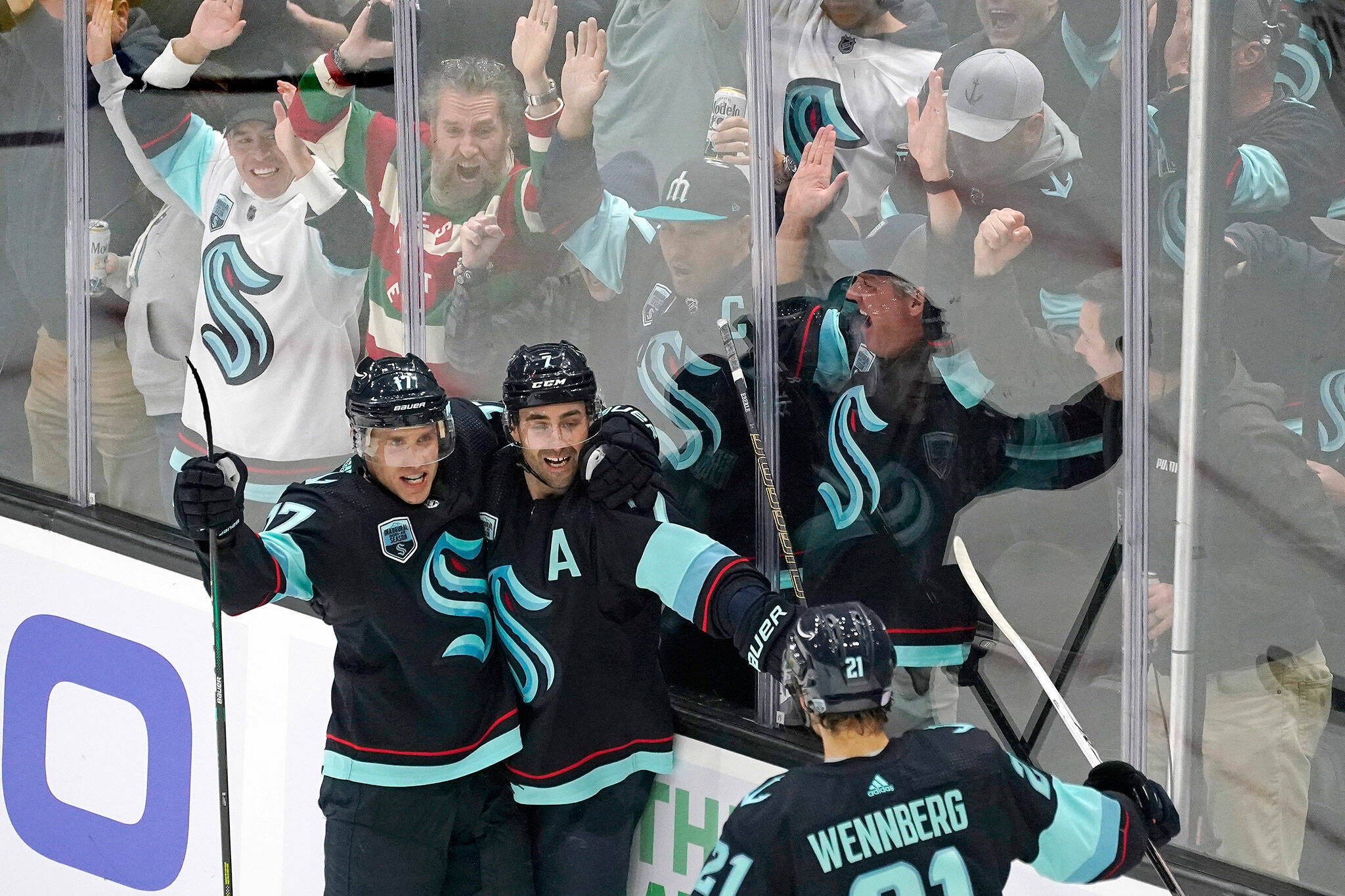 Fans cheer as the Kraken’s Jordan Eberle (center) is congratulated by teammates on his third goal of the night against the Sabres on Thursday in Seattle. (AP Photo/Elaine Thompson)