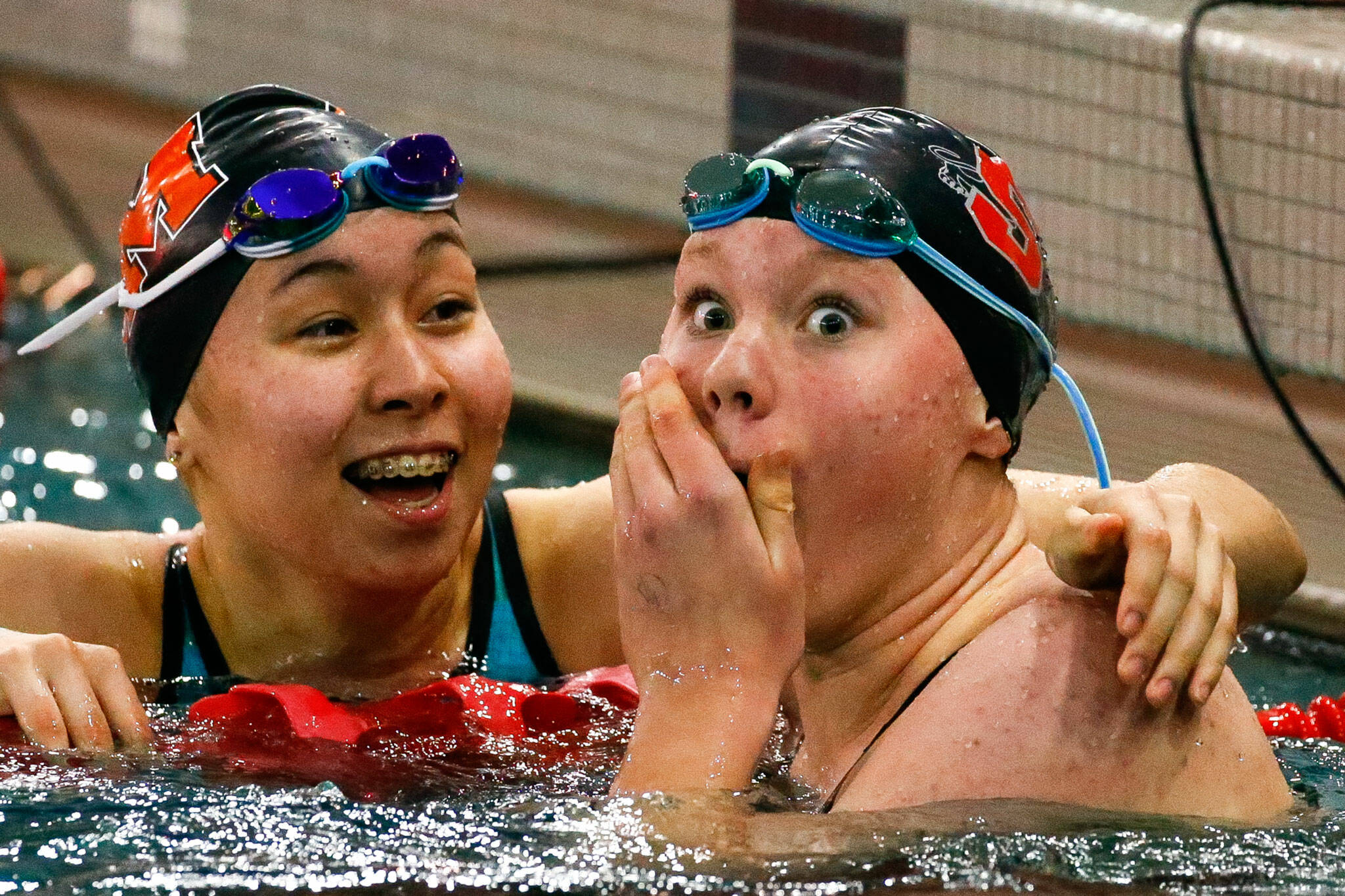 Monroe’s Mia Grove hugs Snohomish’s Mary Clarke for breaking the meet record in the 100 yard freestyle during the 3A District Championships Saturday afternoon the at the Snohomish Aquatic Center on November 6, 2021. (Kevin Clark / The Herald)