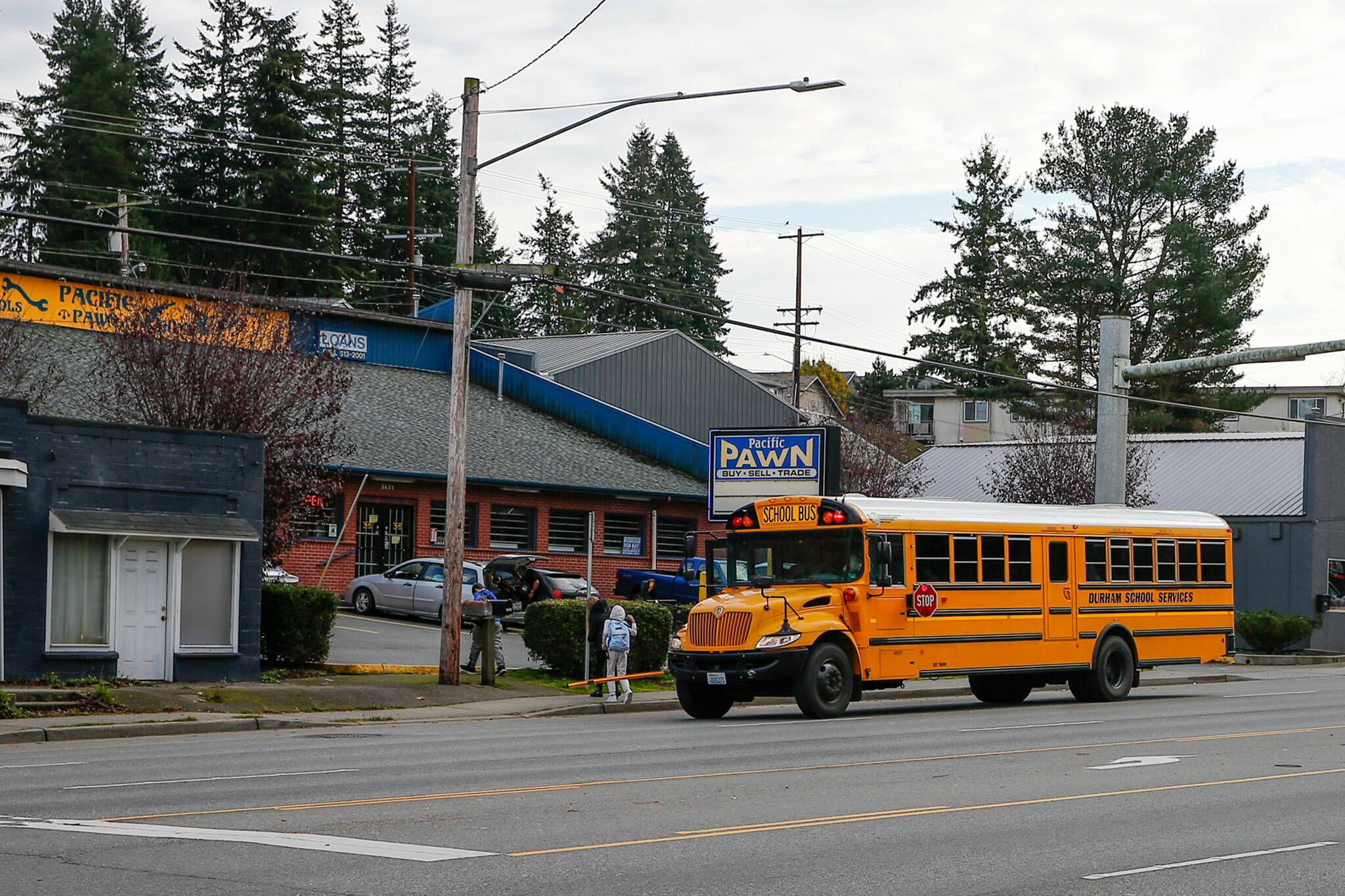 Students unload from a school bus Wednesday afternoon on Evergreen Way in Everett. When a school bus is loading and unloading students and has its stop sign out and red lights flashing, it is illegal to pass from behind. (Kevin Clark / The Herald)