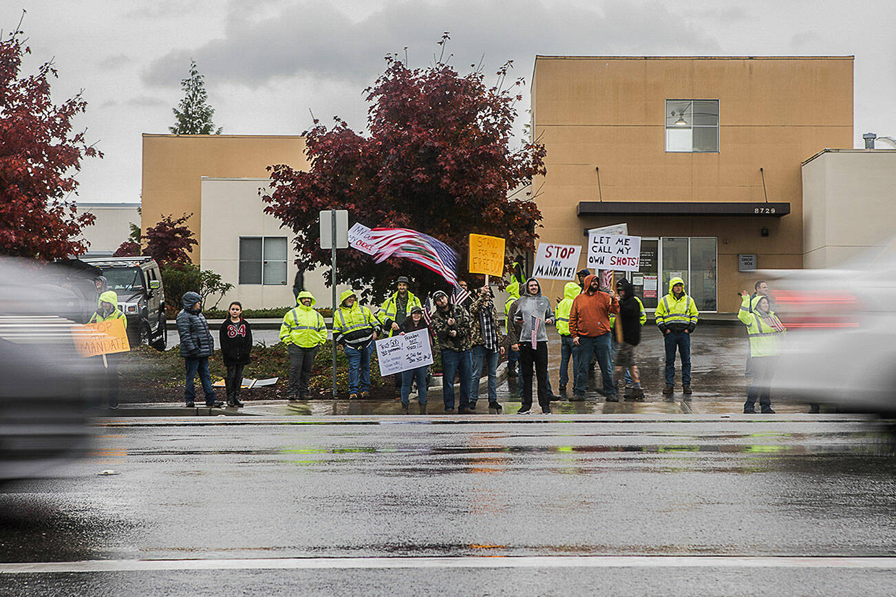 People hold signs in protest of the vaccine mandate along Airport Road next to Boeing on Friday, Oct. 15, 2021 in Everett, Wa. (Olivia Vanni / The Herald)