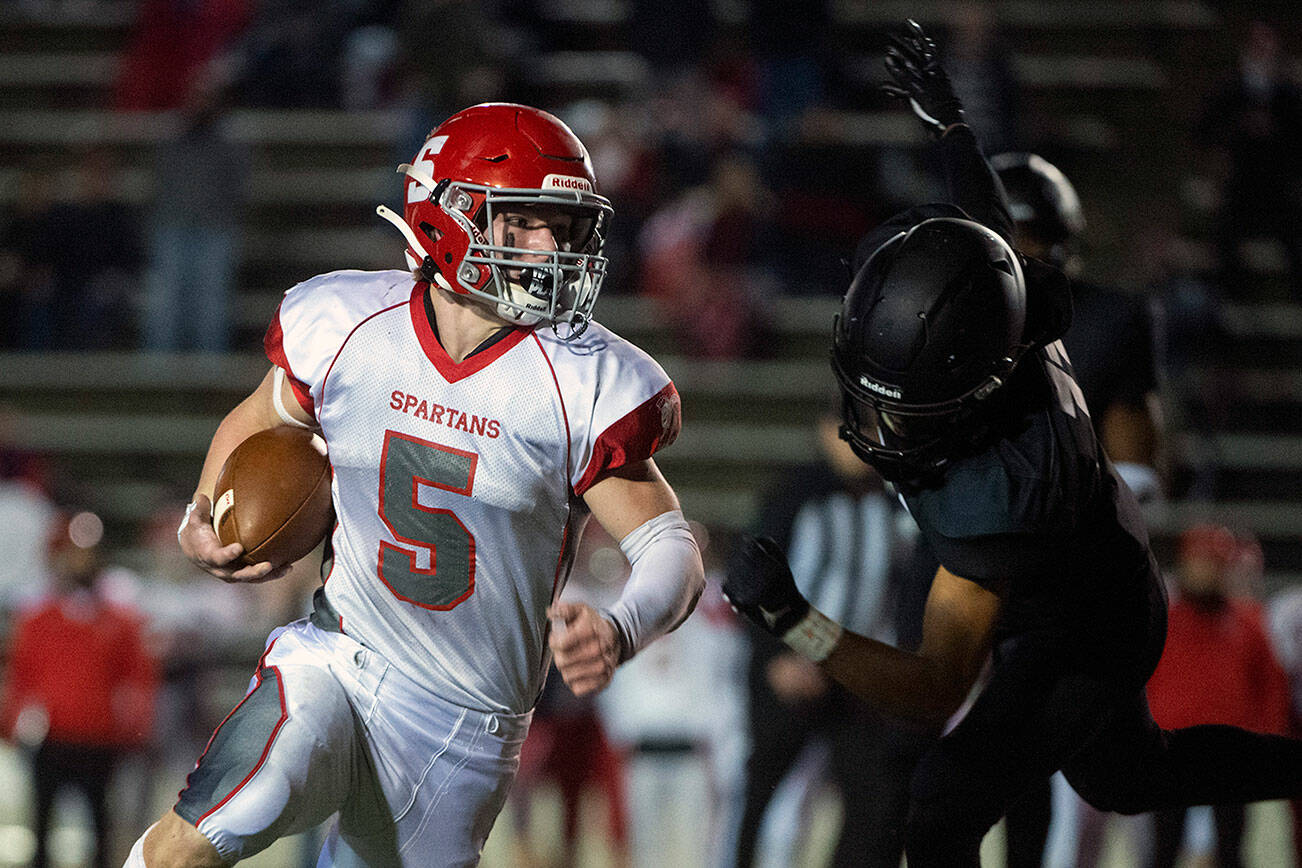 Stanwood running back Ryder Bumgarner turns the corner after evading a tackle attempt by Lincoln’s Drake Cranberry during the first quarter of a 3A winner-to-state playoff game at the Lincoln Bowl in Tacoma on Nov. 5, 2021. (Pete Caster / The News Tribune)